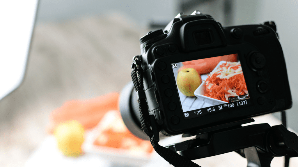 DSLR camera snapping a photo of a salad and an apple. This way restaurant and takeaways get to update customers to help their social media marketing.